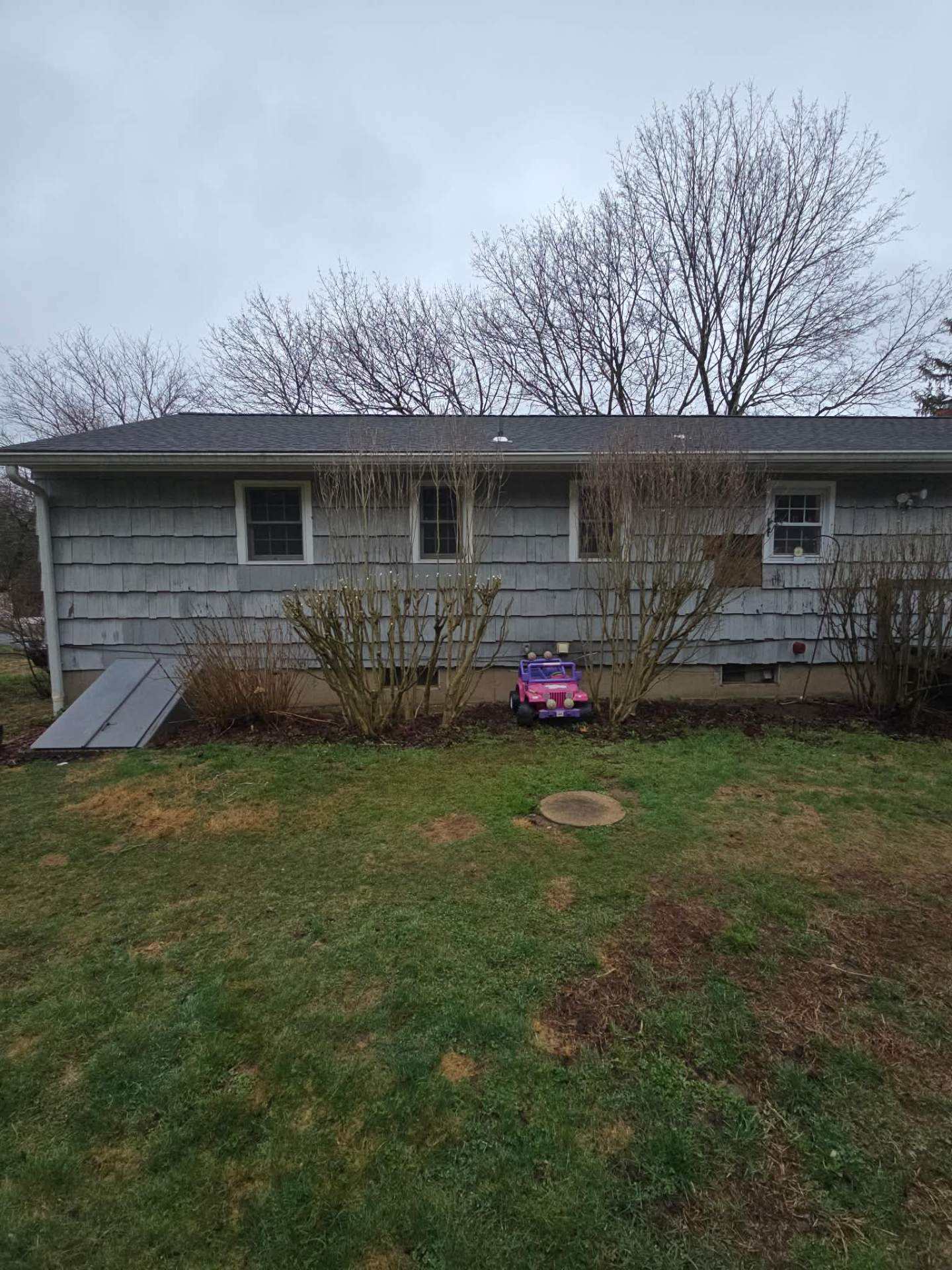 Back of a ranch house with the yard cleared and lawn open after shrub removal